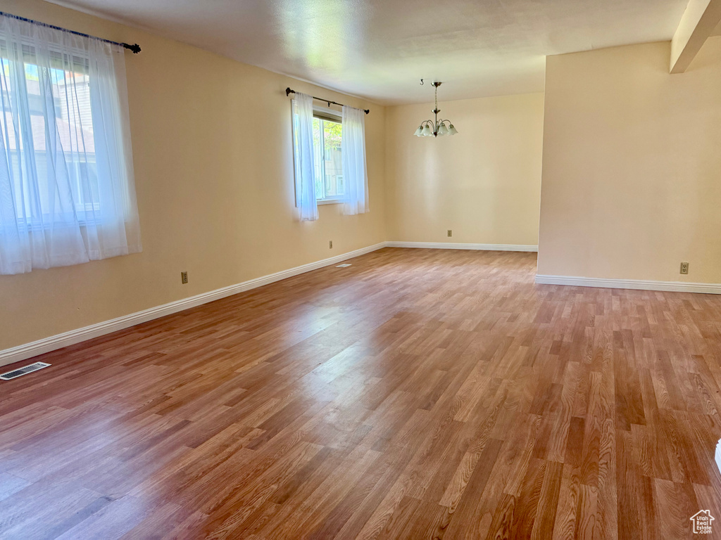 Unfurnished room with a chandelier and light wood-style floors