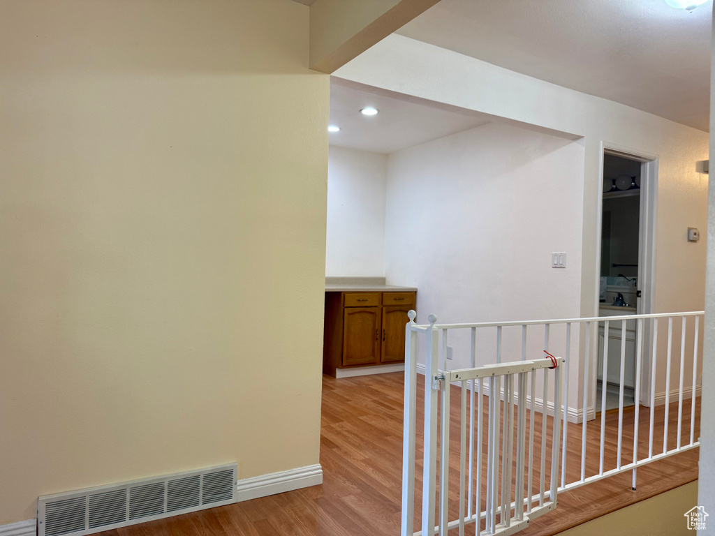 Hallway featuring light wood-style floors, recessed lighting, and an upstairs landing
