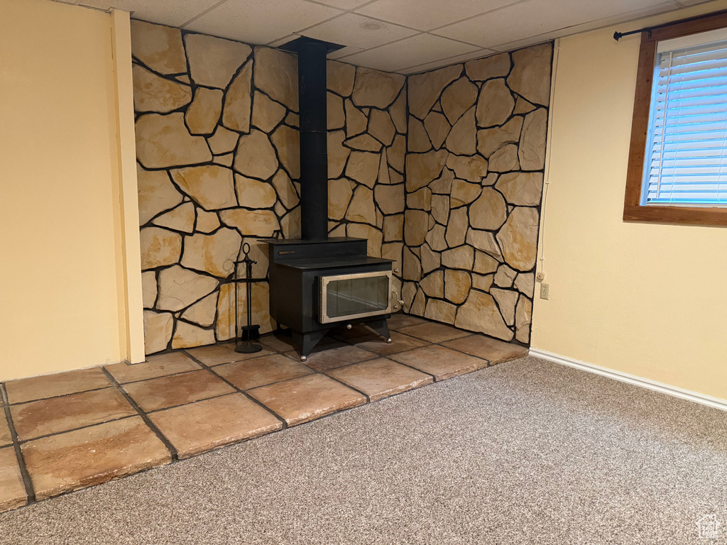 Detailed view of carpet flooring, a wood stove, and a paneled ceiling