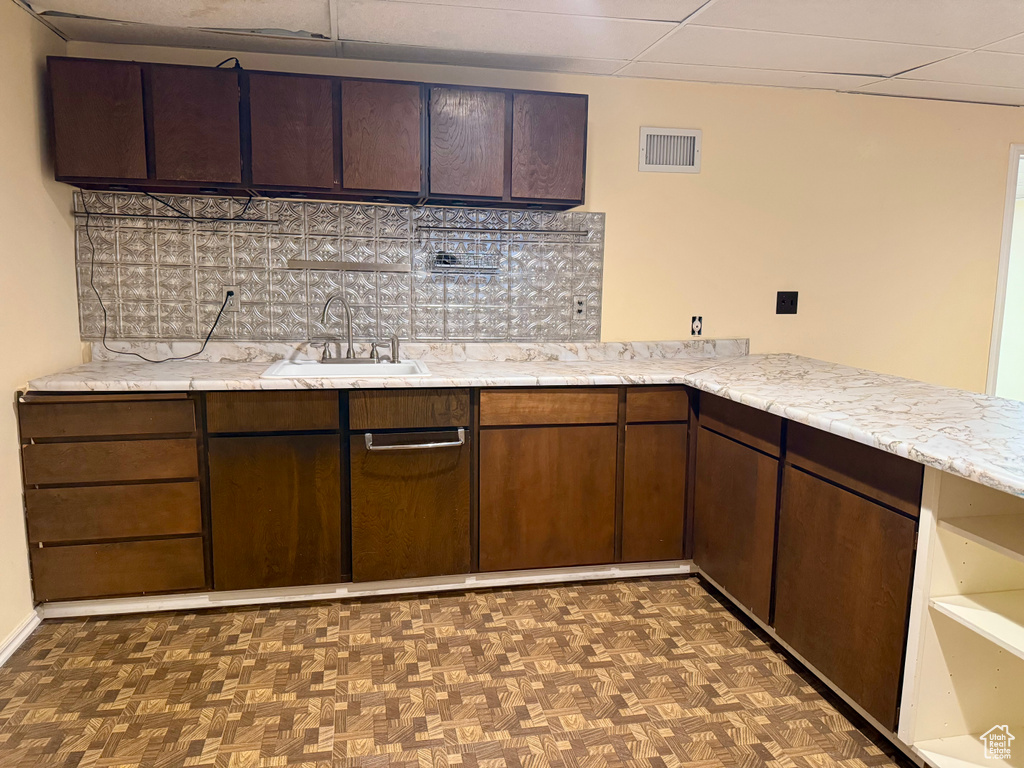 Kitchen featuring decorative backsplash, dark brown cabinets, and light stone countertops