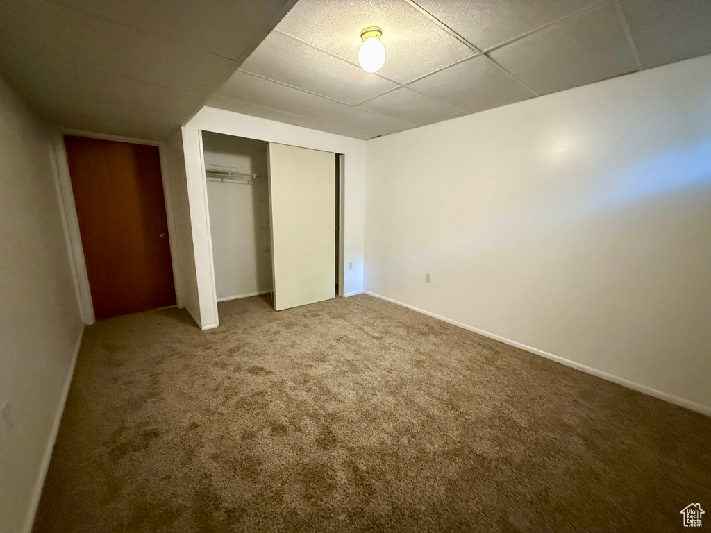 Unfurnished bedroom featuring carpet floors, a drop ceiling, and a closet