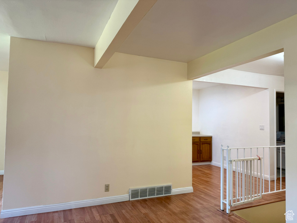 Unfurnished room with wood finished floors and beam ceiling
