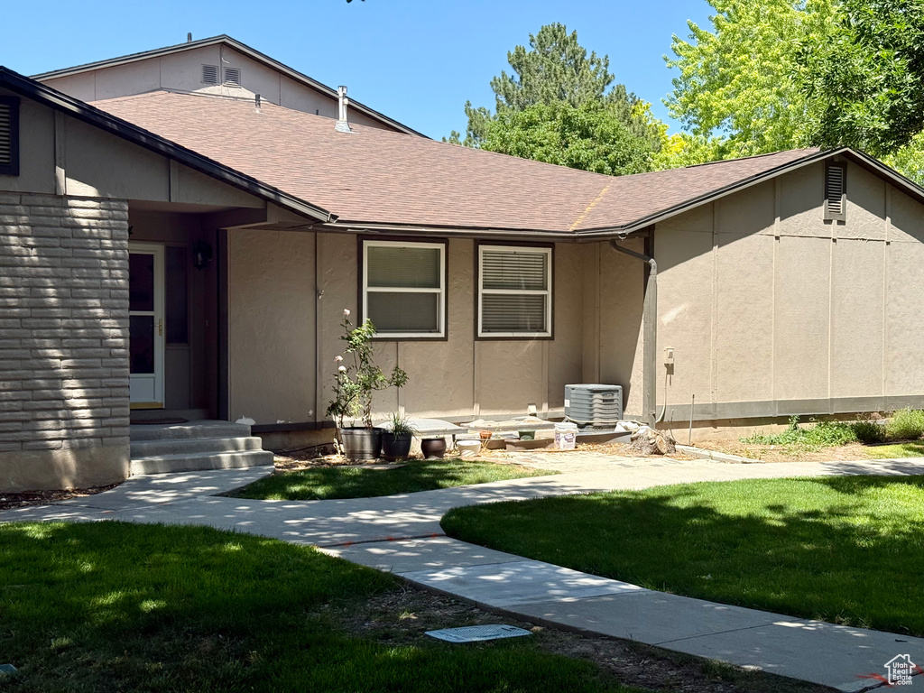 View of front of property with a front yard, roof with shingles, and entry steps