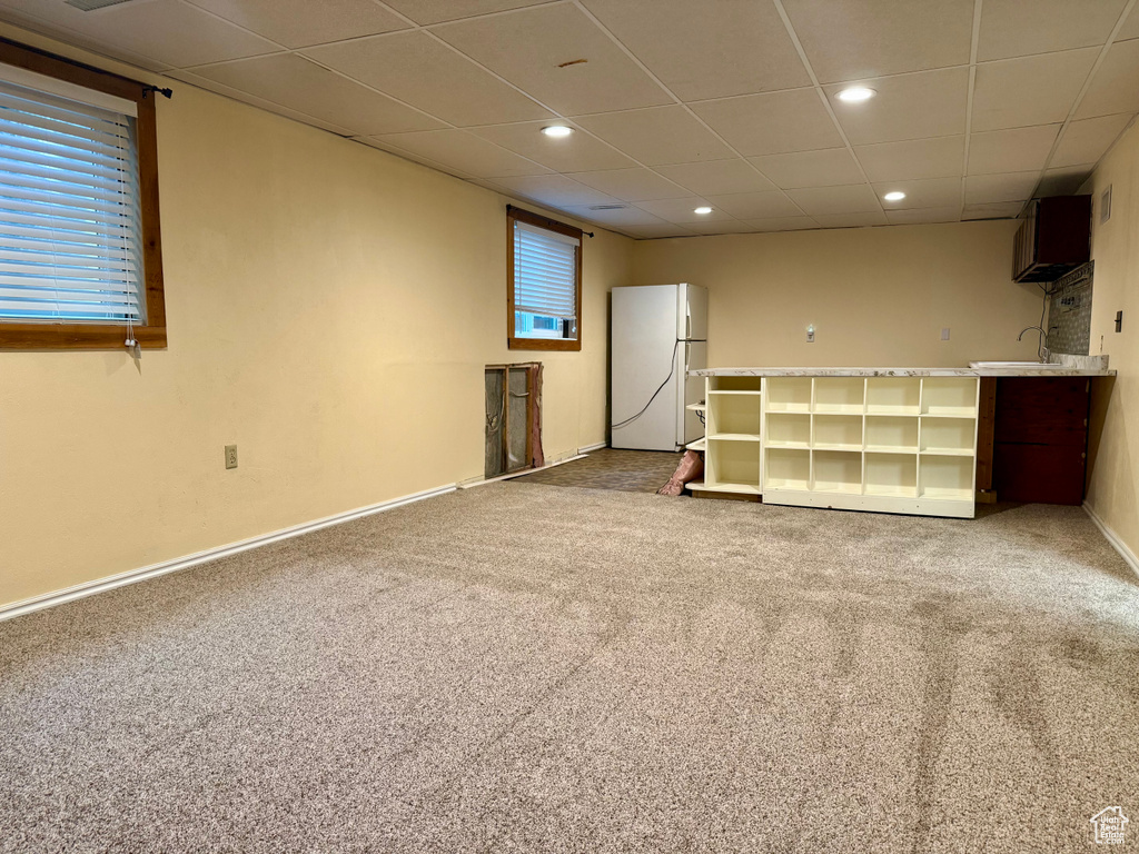 Finished below grade area featuring freestanding refrigerator, carpet flooring, a drop ceiling, and recessed lighting