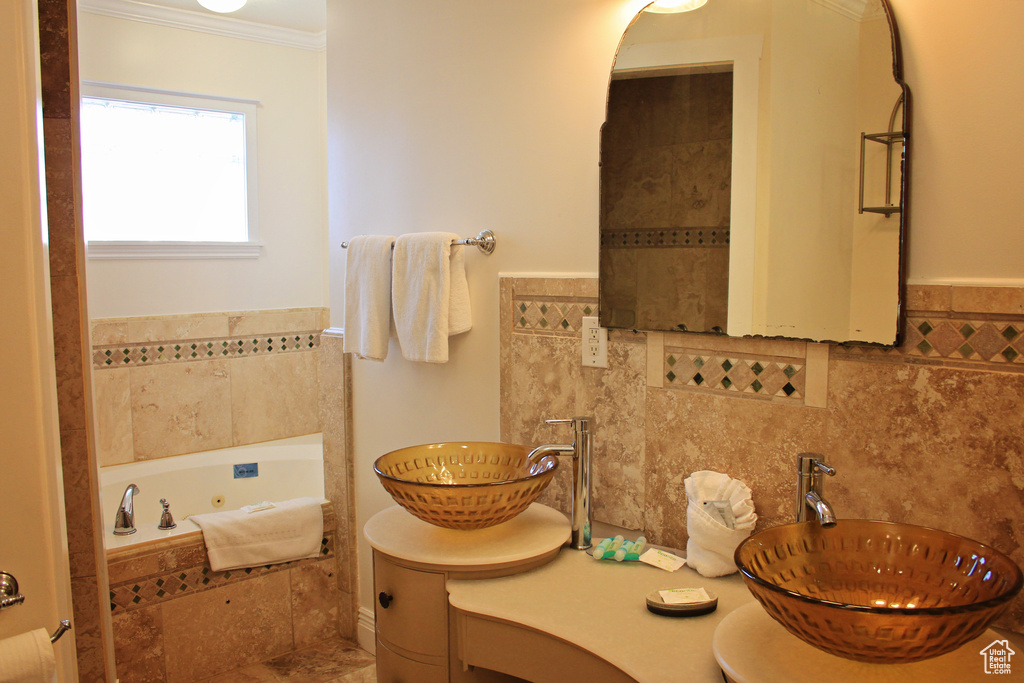 Full bathroom featuring ornamental molding, double vanity, and a tub with jets
