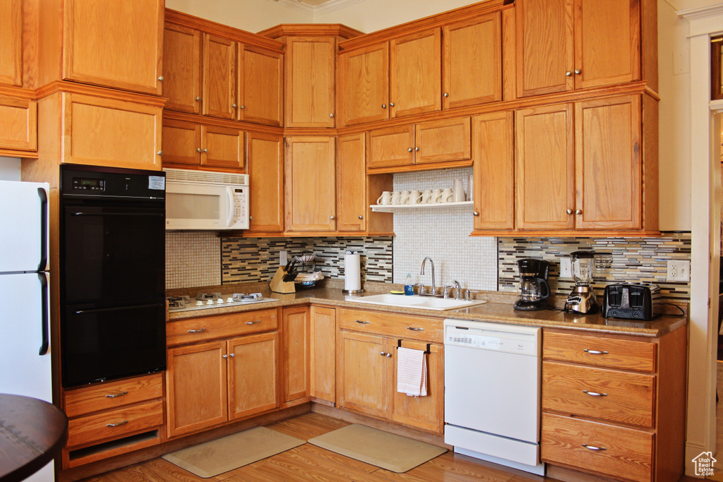 Kitchen with white appliances, ornamental molding, decorative backsplash, light wood-style floors, and open shelves