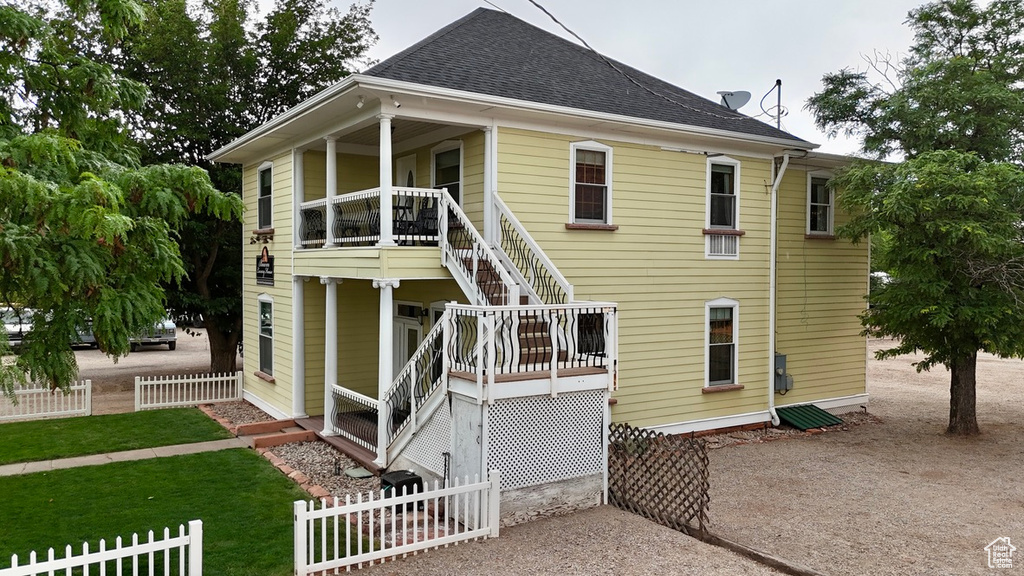 Back of house featuring stairs and roof with shingles