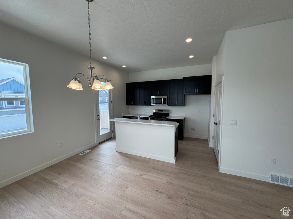 Kitchen with stainless steel appliances, dark cabinetry, a chandelier, recessed lighting, and light wood-style flooring