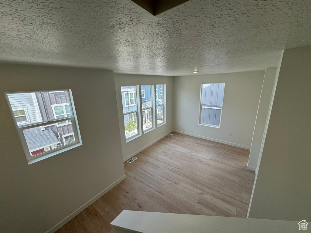 Unfurnished room featuring light wood finished floors and a textured ceiling