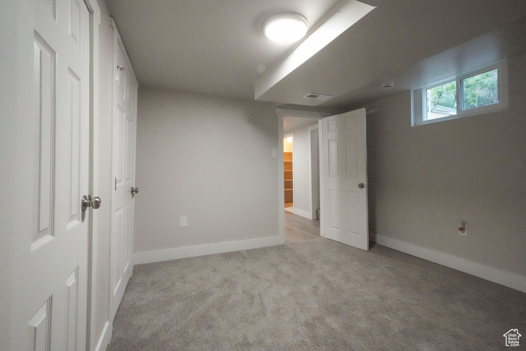 Unfurnished bedroom featuring light carpet and baseboards