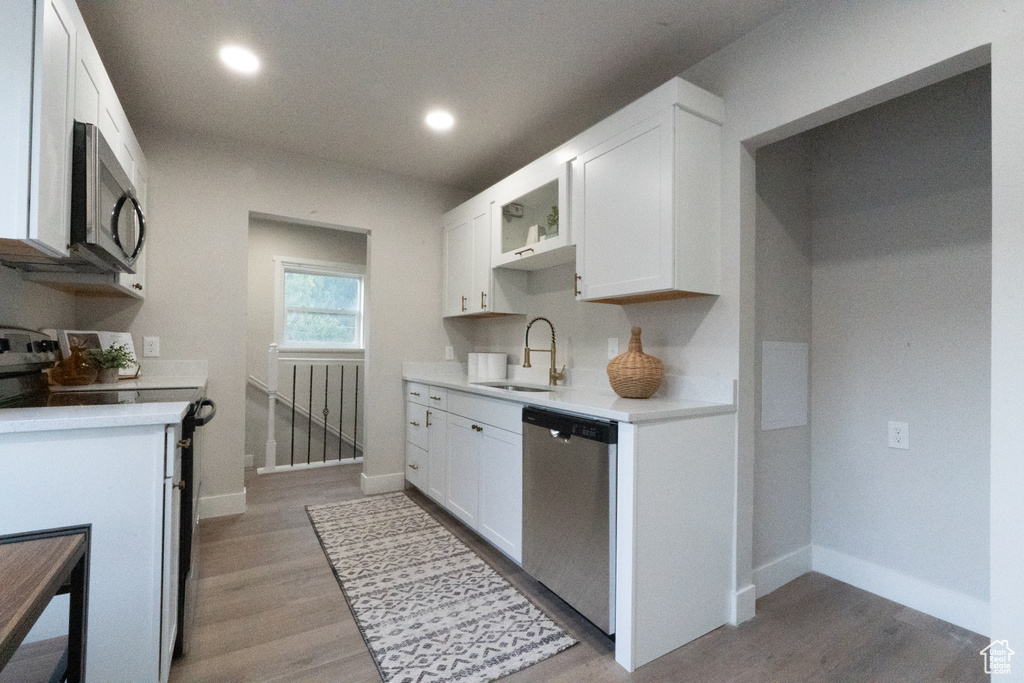 Kitchen with appliances with stainless steel finishes, light countertops, light wood-style flooring, white cabinetry, and recessed lighting