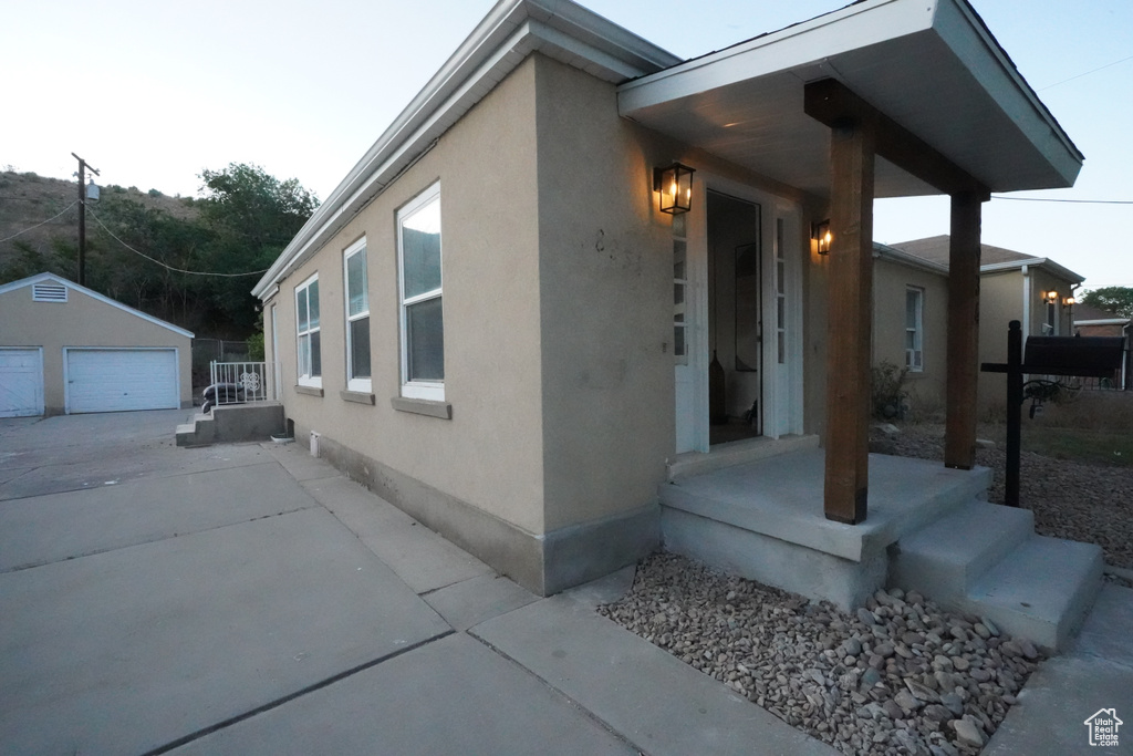 View of side of home featuring an outdoor structure, stucco siding, and a detached garage