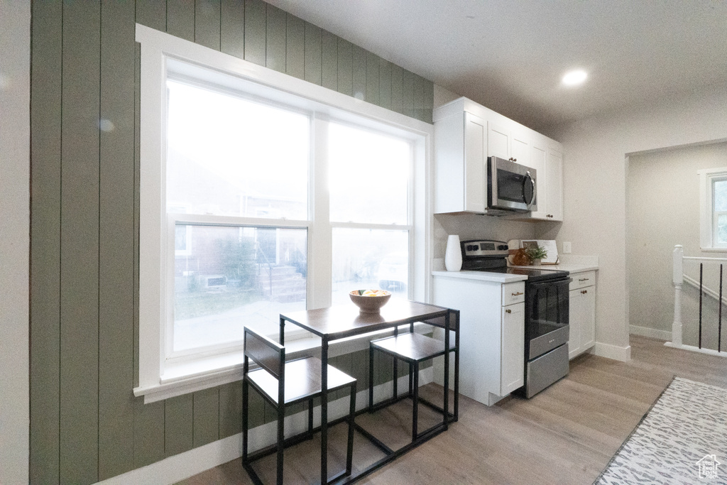 Kitchen featuring stainless steel appliances, white cabinetry, light wood finished floors, light countertops, and recessed lighting