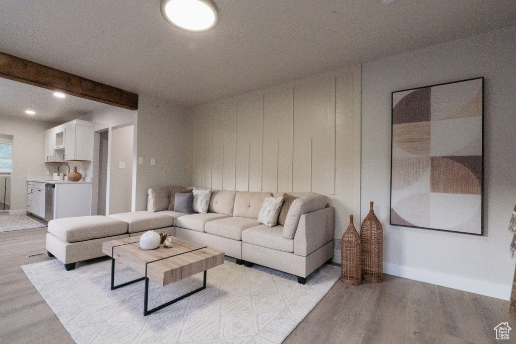 Living area featuring light wood-style floors and beamed ceiling