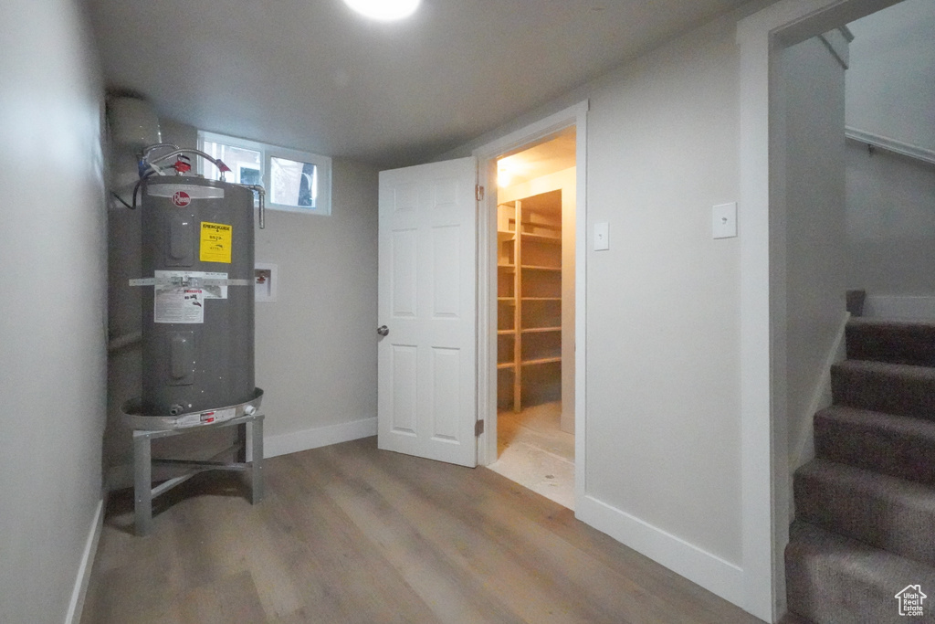 Basement featuring water heater, wood finished floors, and stairs