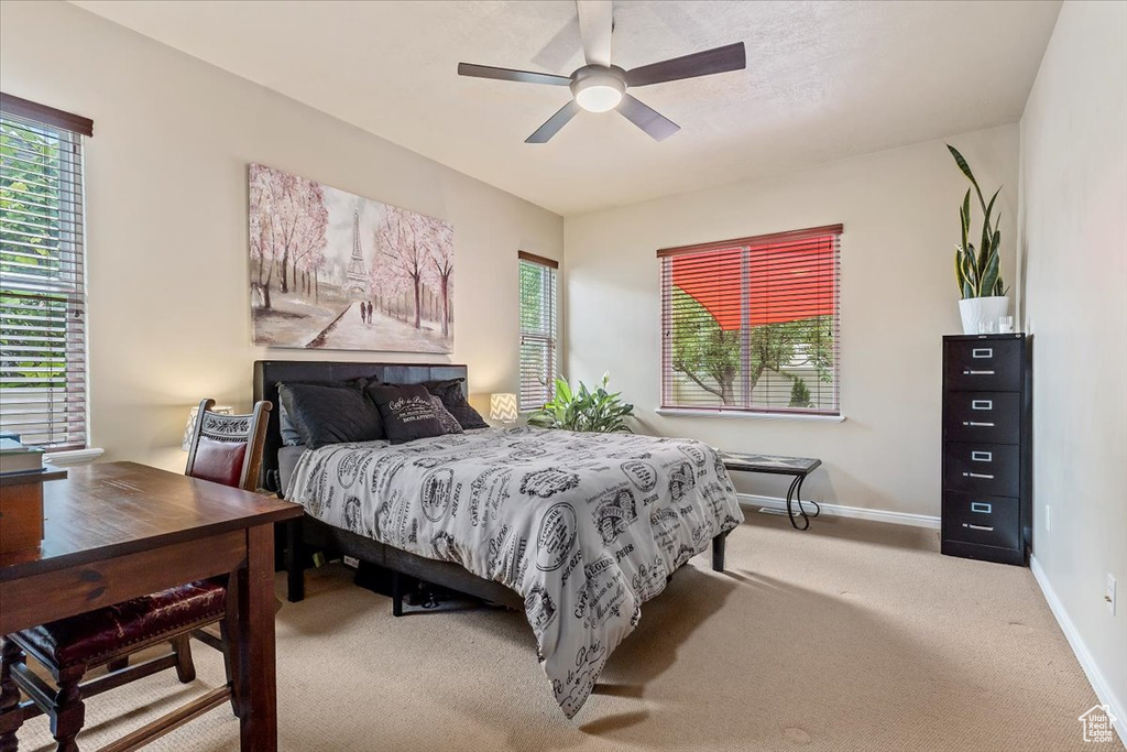 Bedroom with multiple windows, light carpet, and a ceiling fan