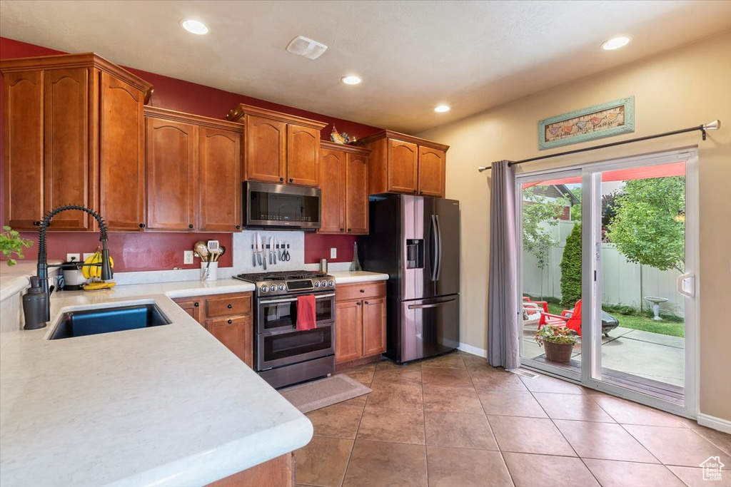 Kitchen with stainless steel appliances, light countertops, brown cabinets, recessed lighting, and light tile patterned flooring