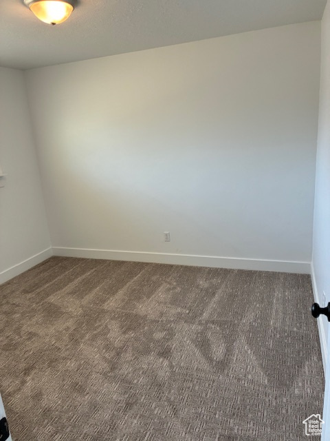 Spare room featuring carpet flooring and baseboards