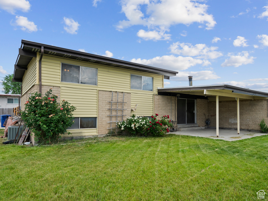 Rear view of property featuring a patio, brick siding, and a yard
