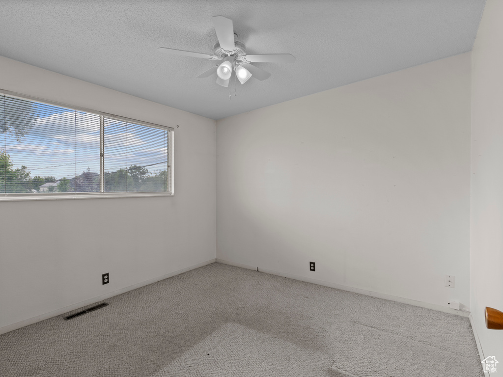 Carpeted spare room featuring a ceiling fan and a textured ceiling