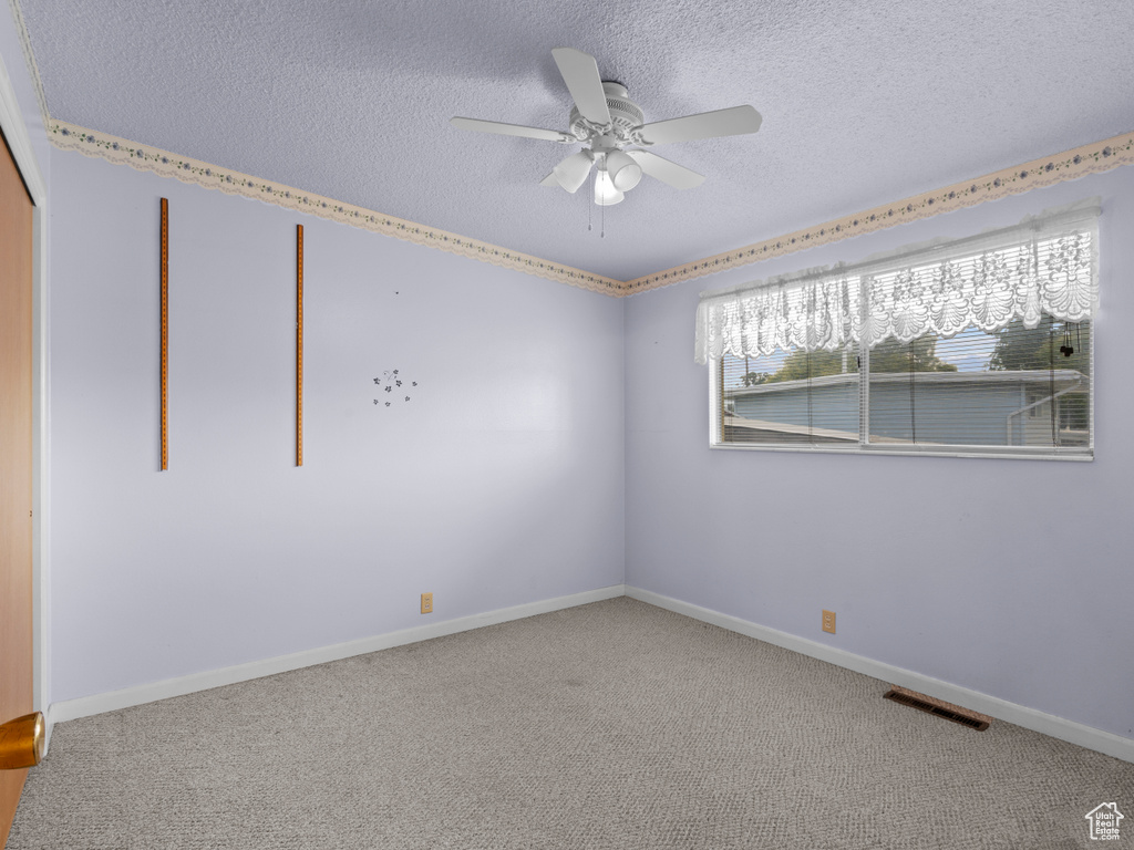 Carpeted spare room with a textured ceiling and ceiling fan