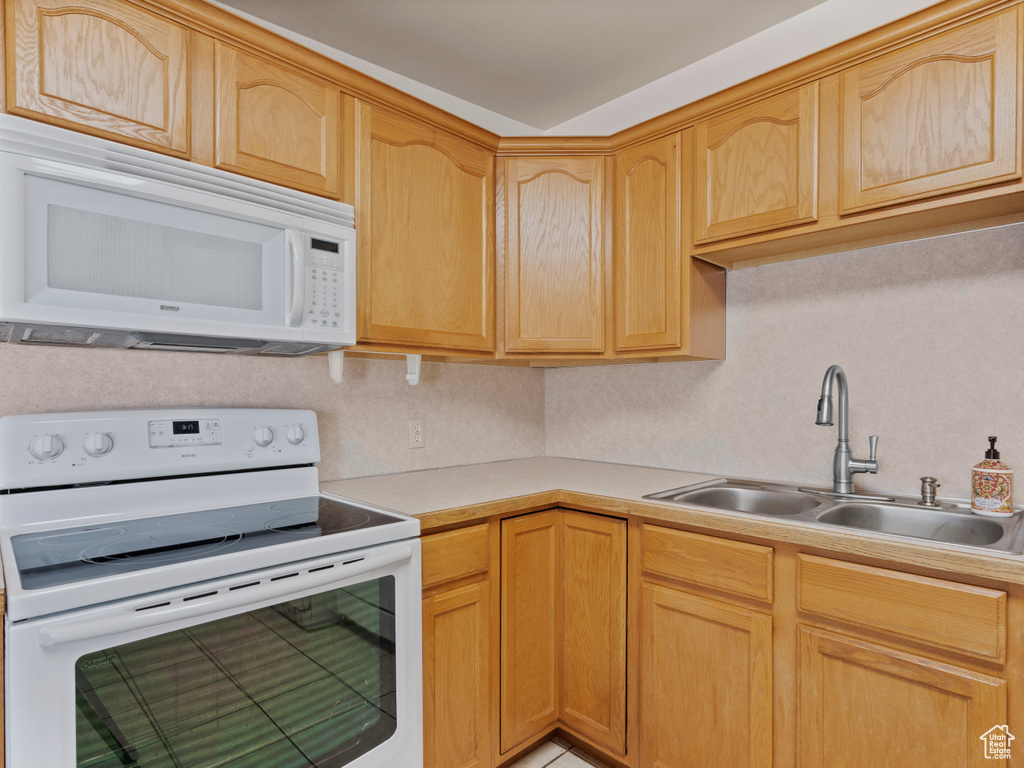 Kitchen with white appliances, light countertops, and light brown cabinetry