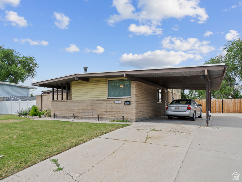 View of front of home featuring brick siding, concrete driveway, and a carport