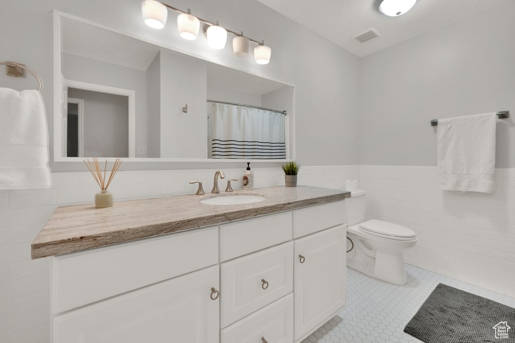 Full bathroom with tile walls, vanity, and wainscoting
