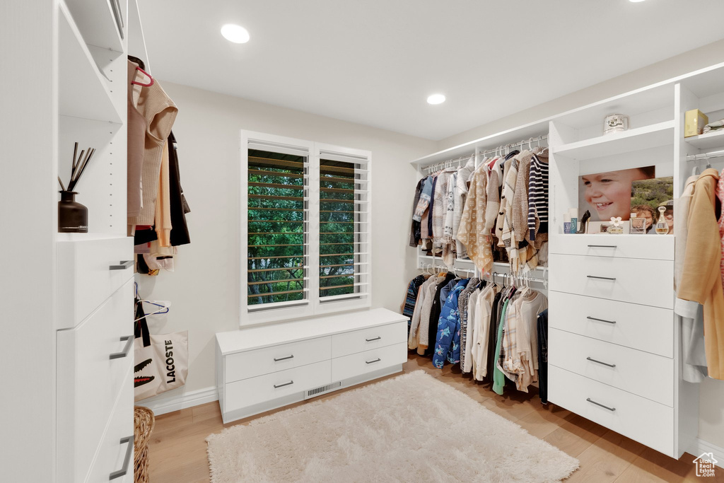 Walk in closet with light wood finished floors