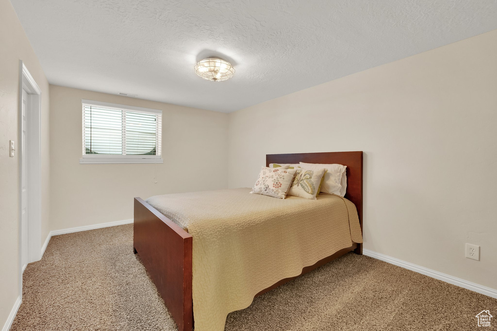 Bedroom with light colored carpet and a textured ceiling