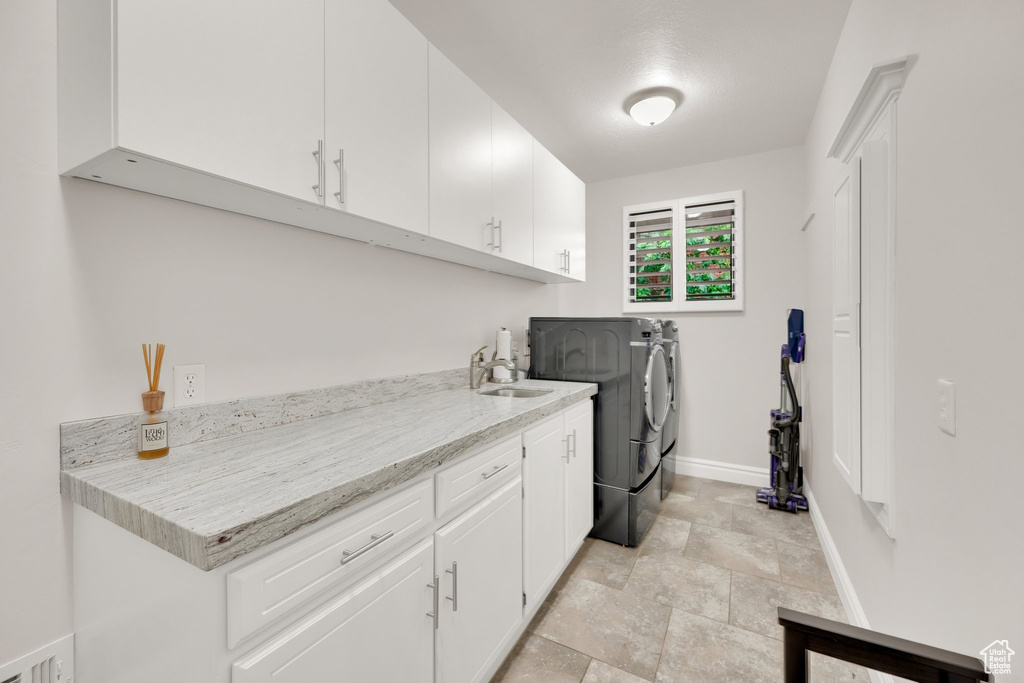 Washroom featuring washer and dryer, cabinet space, and stone finish flooring