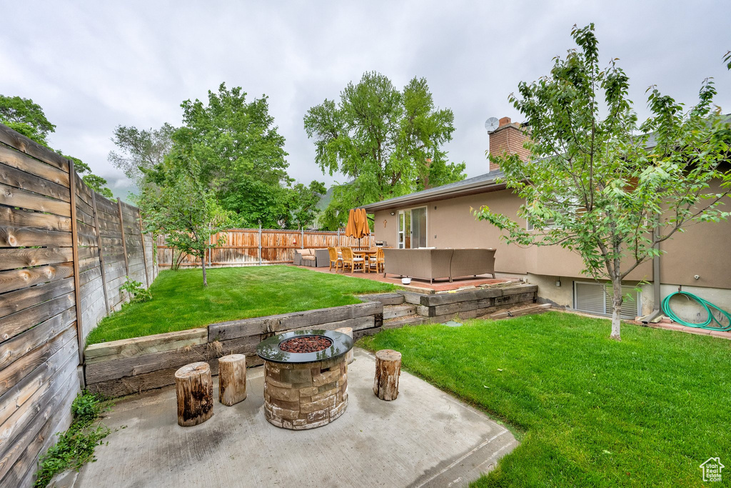 Fenced backyard featuring an outdoor fire pit and a patio area