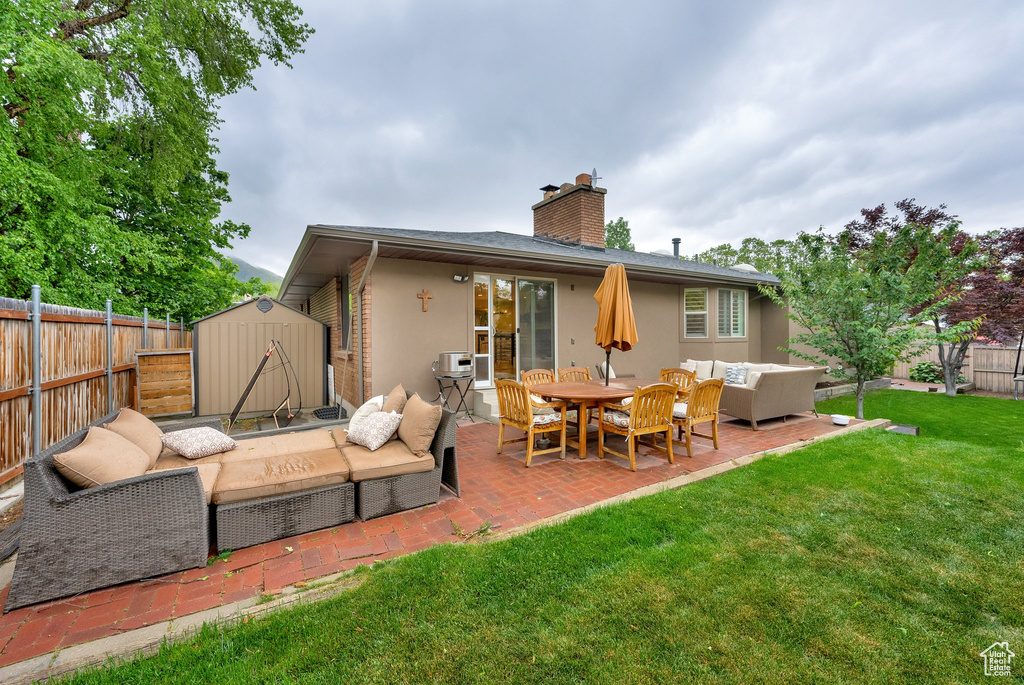 Back of house featuring an outdoor hangout area, a storage unit, a patio, and a fenced backyard
