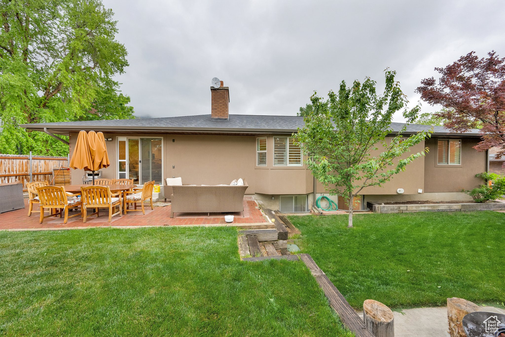 Rear view of property with an outdoor living space, a chimney, a patio area, and stucco siding