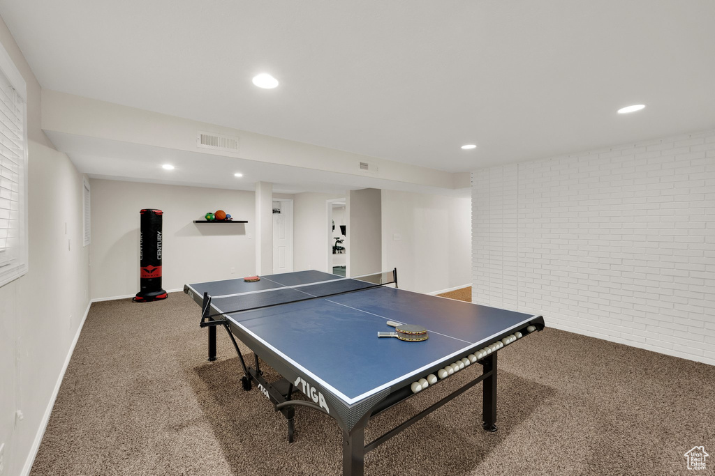 Recreation room with carpet floors, brick wall, and recessed lighting