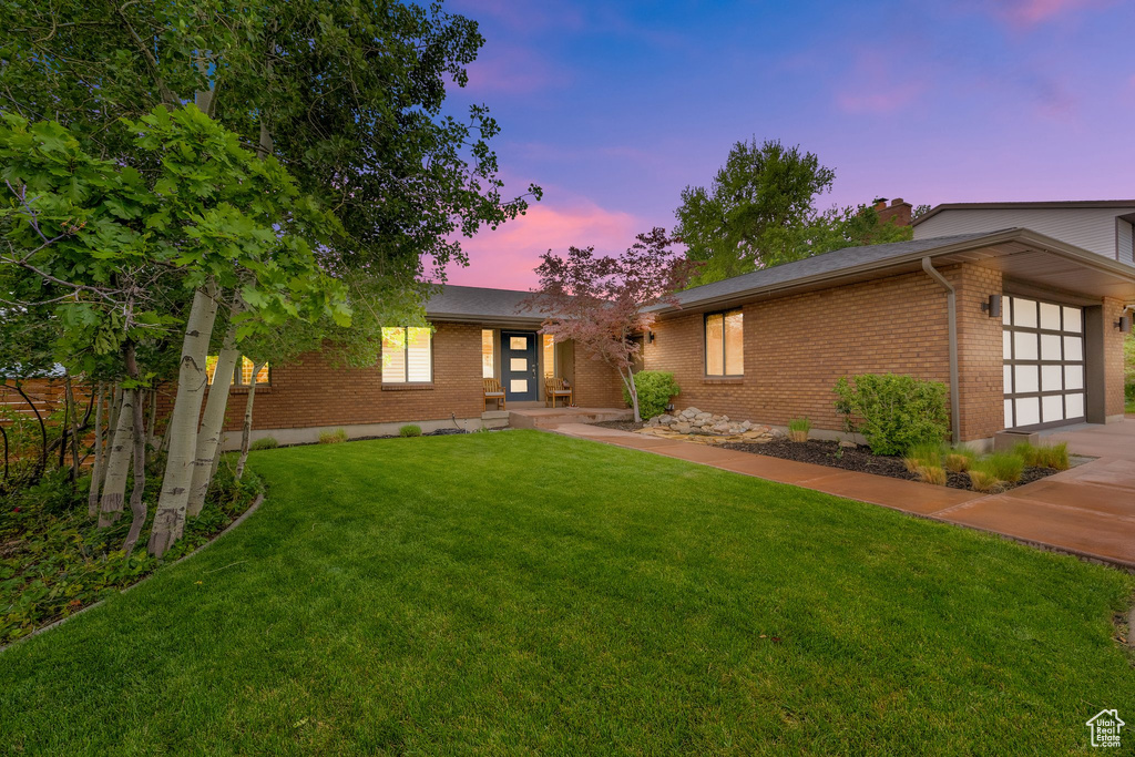 View of front of property featuring brick siding, an attached garage, a front yard, and concrete driveway
