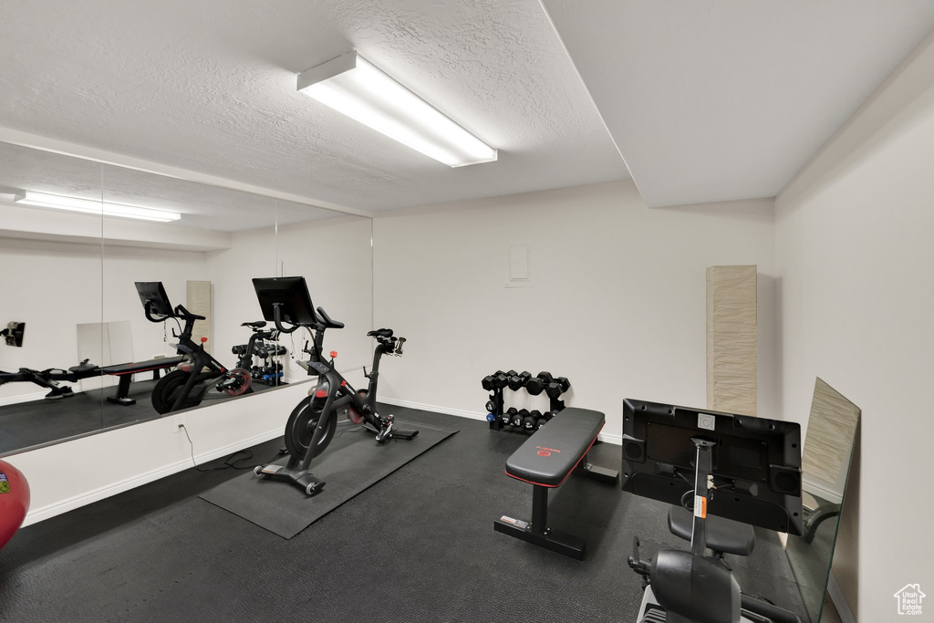 Exercise area featuring a textured ceiling and baseboards