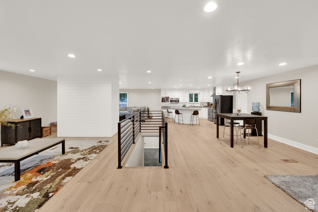 Living area featuring light wood-type flooring, recessed lighting, and a chandelier