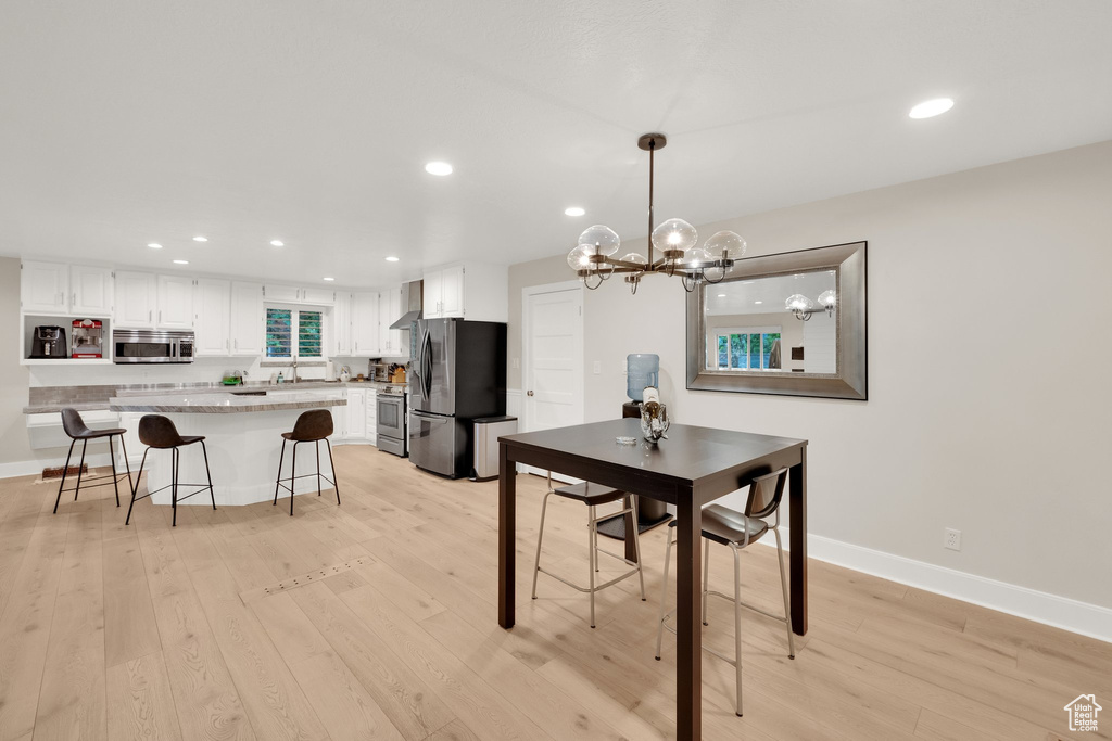 Dining room with light wood finished floors, recessed lighting, and a chandelier