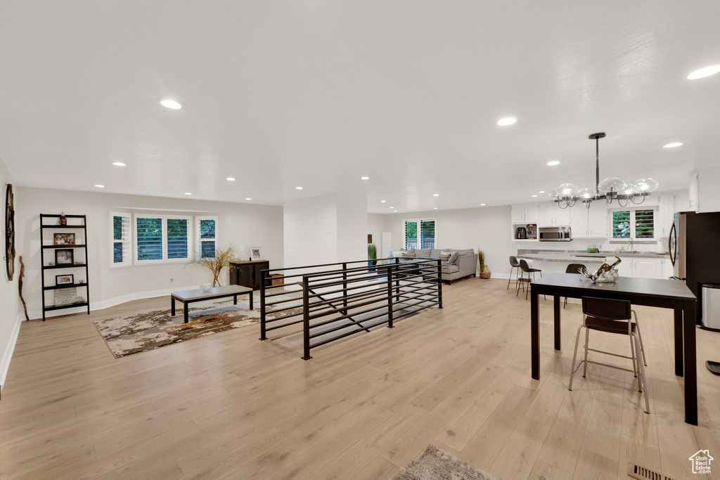 Living area with a chandelier, light wood-style floors, and recessed lighting