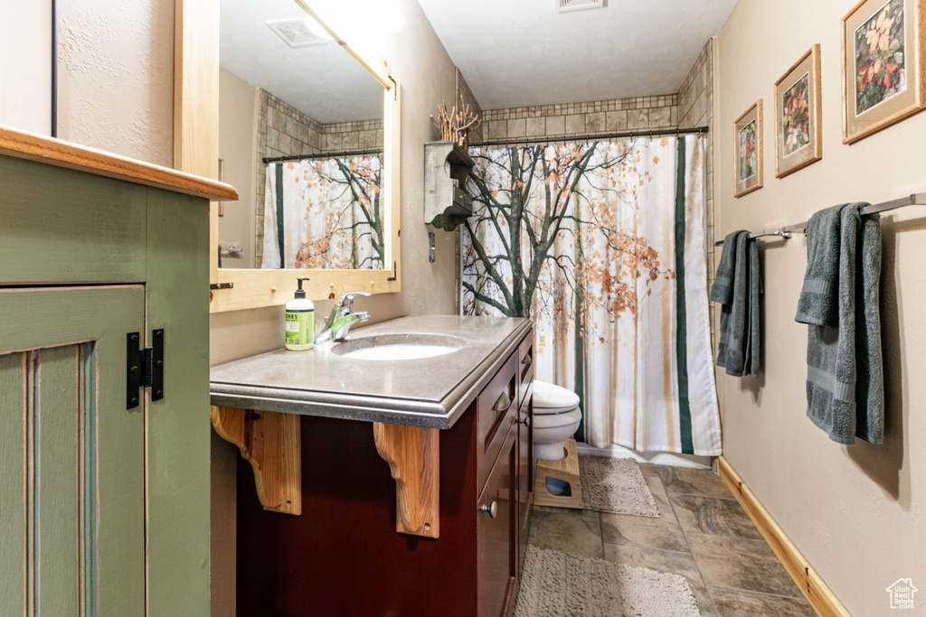 Full bathroom with vanity, stone finish floors, and curtained shower