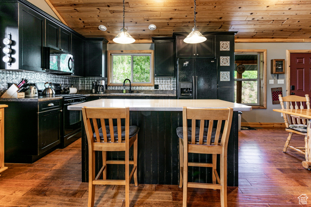 Kitchen with black appliances, dark cabinetry, wood ceiling, decorative backsplash, and dark wood finished floors