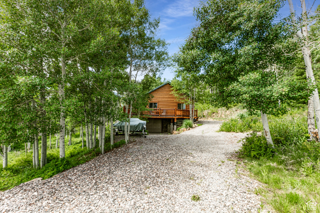 View of side of home featuring a deck and gravel driveway