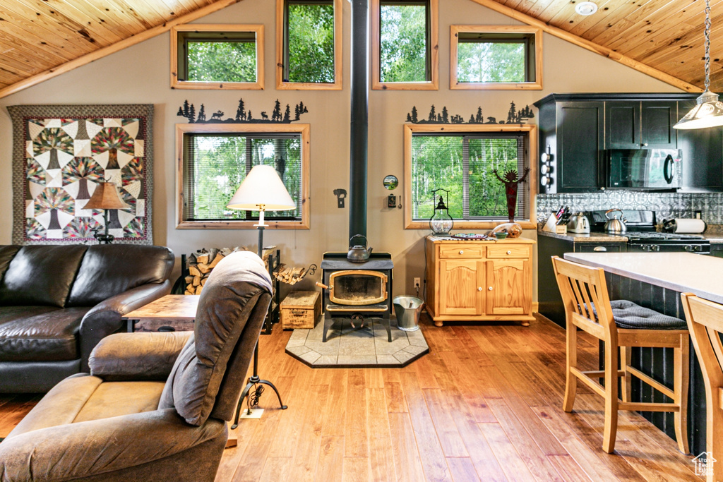 Living area with wood ceiling, a wood stove, light wood-style floors, plenty of natural light, and high vaulted ceiling