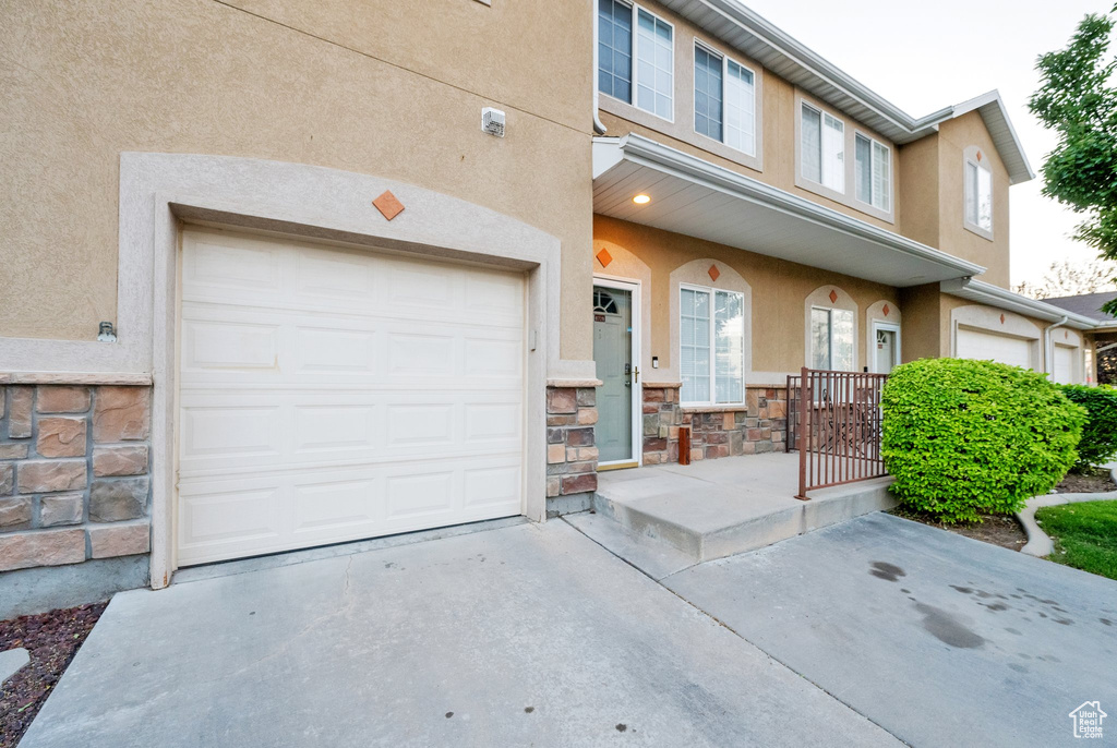 View of front of home featuring stucco siding, driveway, stone siding, and an attached garage
