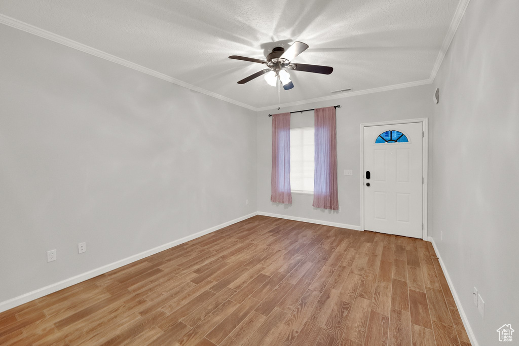 Foyer featuring crown molding, ceiling fan, and light wood-style floors