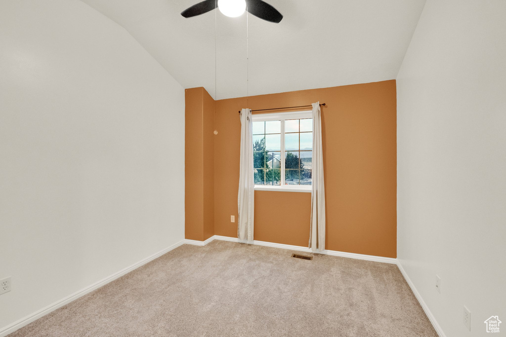 Carpeted spare room with vaulted ceiling and a ceiling fan