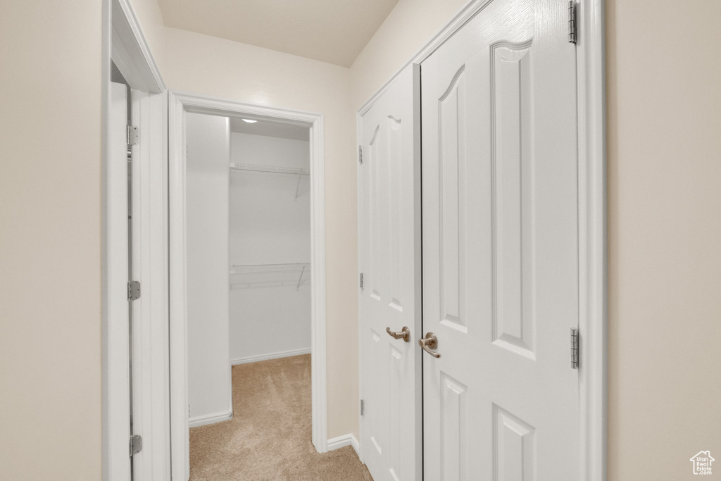 Hallway featuring light colored carpet and baseboards