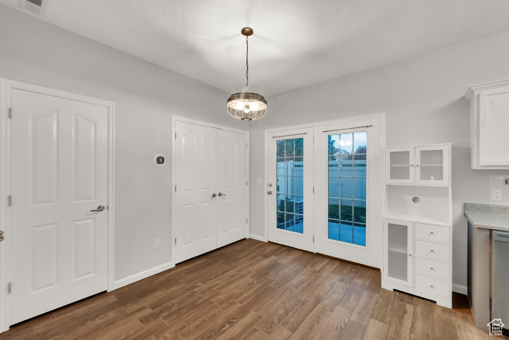 Unfurnished dining area with wood finished floors and a chandelier