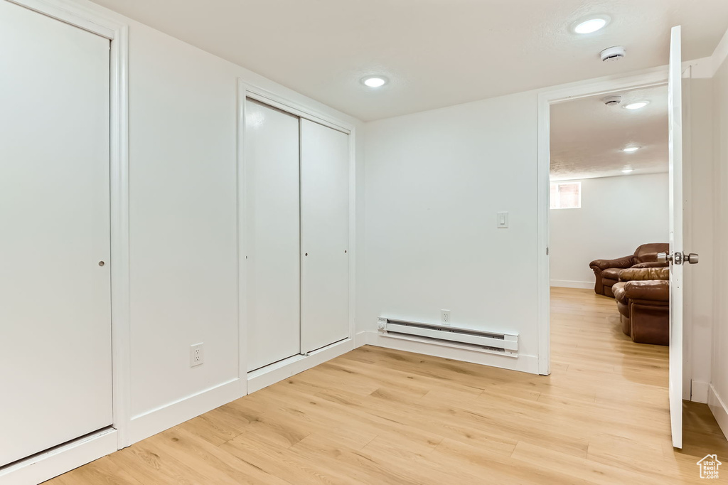 Bedroom featuring a baseboard radiator, light wood finished floors, recessed lighting, and a closet
